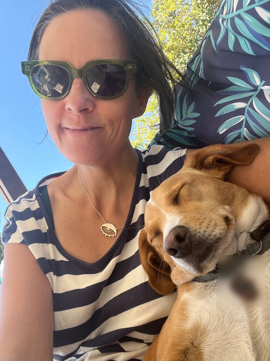 Hilary in sunglasses with a sleeping tan and white dog resting on her arm