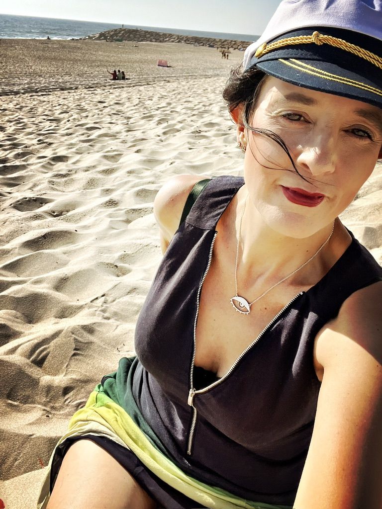 Hilary in a captain's hat relaxing on a sandy beach